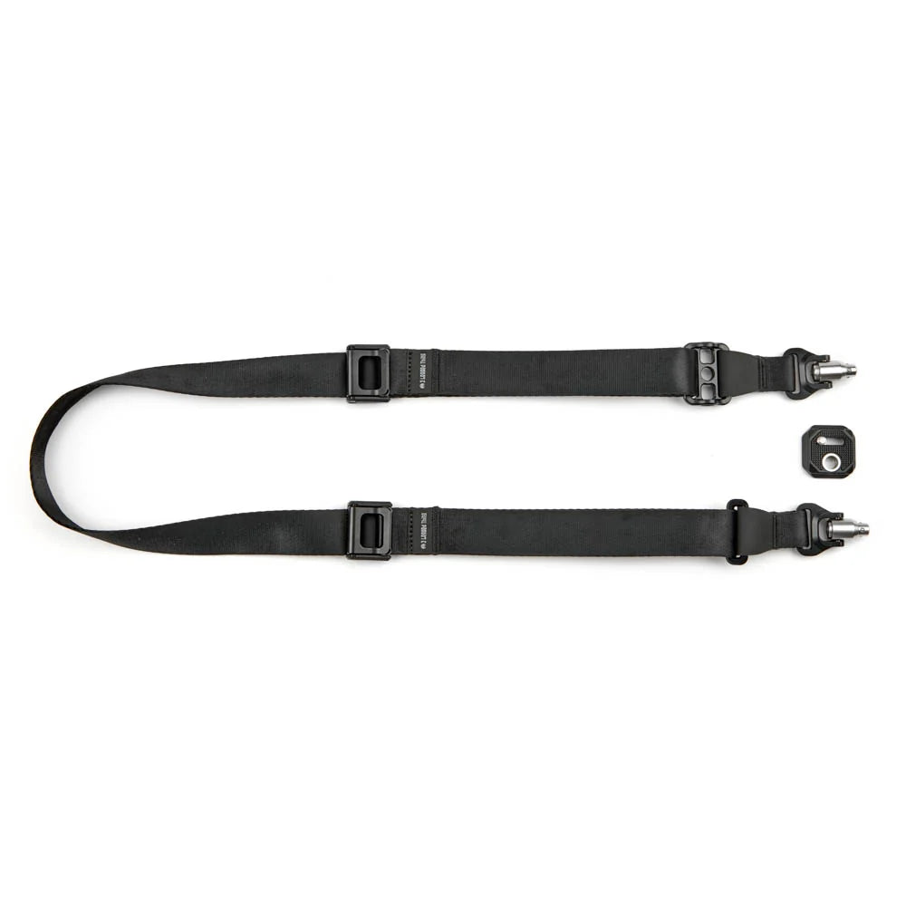 Black camera strap with dual quick-release buckles, metal tip connectors, and a small matching black accessory piece on a plain white background.