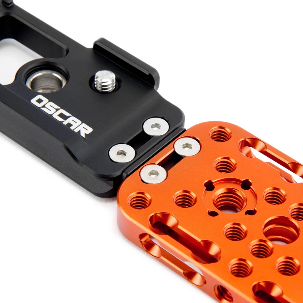 Close-up of a black and orange metal mechanical component with visible screws and the brand name OSCAR on the black section, photographed on a white background.
