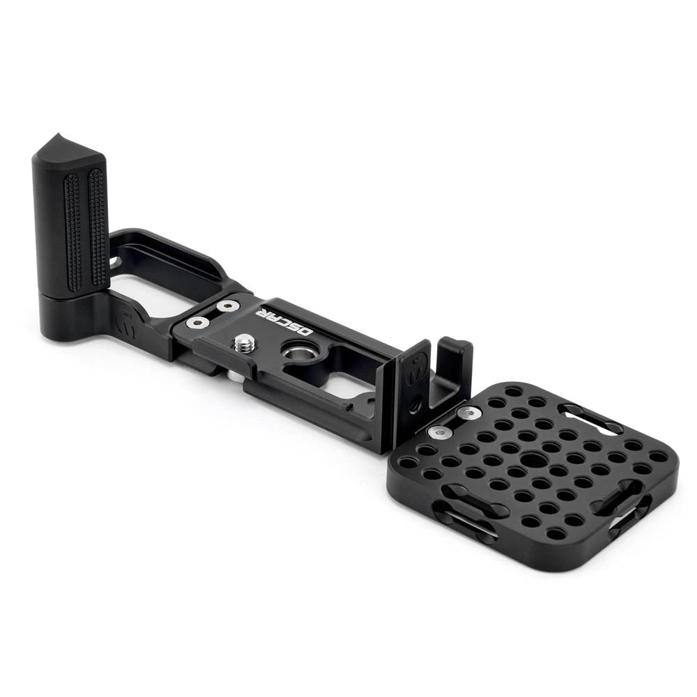 A black metal camera grip extension with a textured vertical grip and a perforated mounting plate, shown on a clean white background.