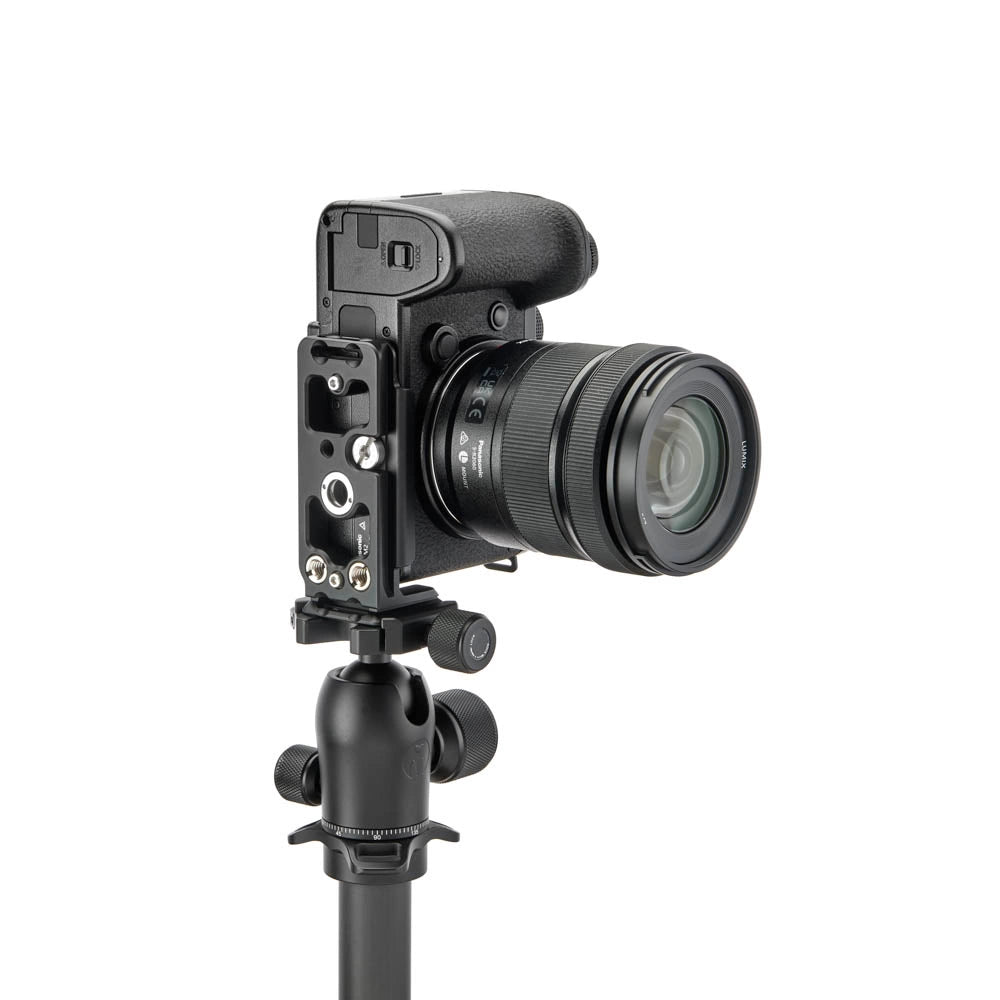 A black Lumix camera with a lens attached, mounted on a black tripod head, shown against a plain white background.