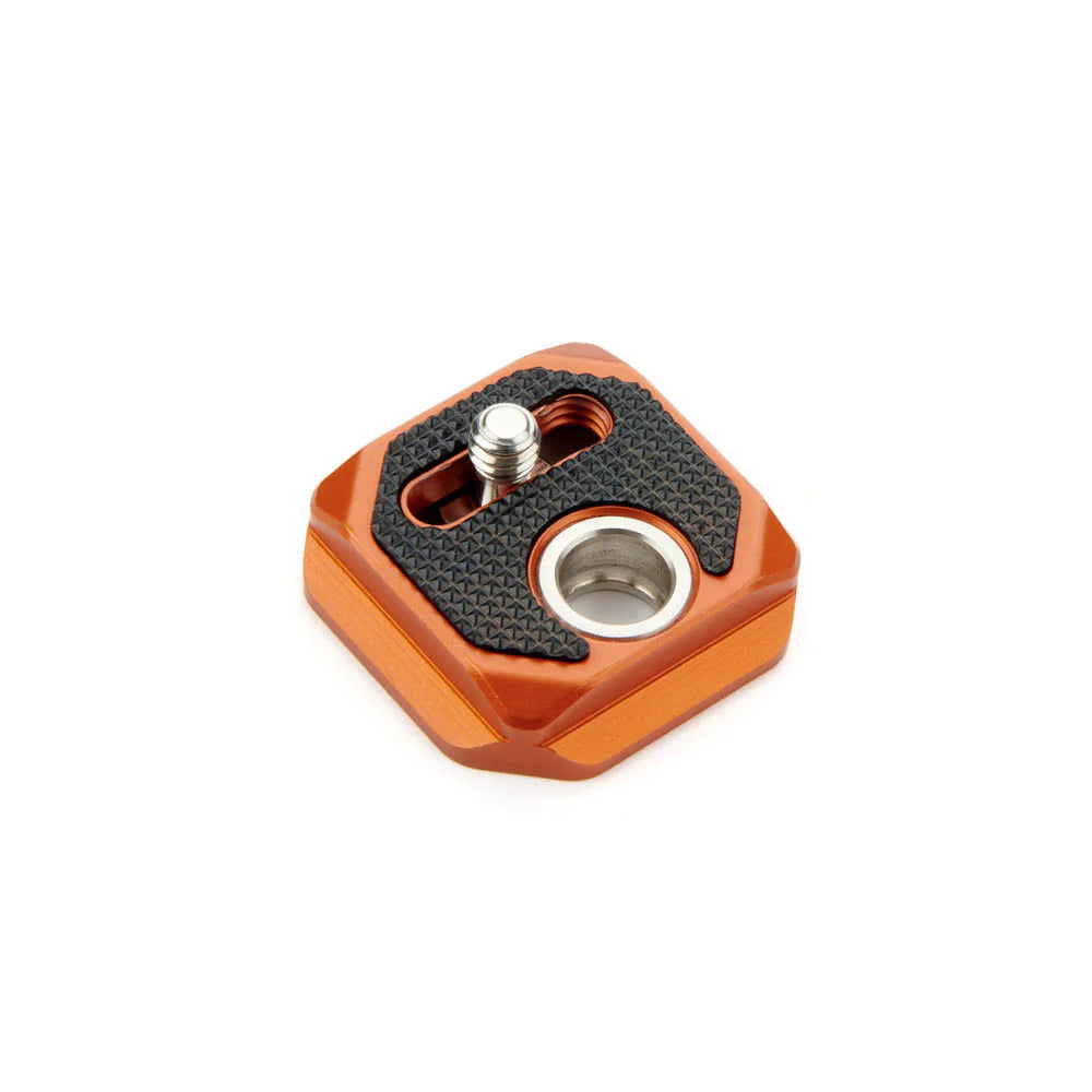 An orange anodized aluminum camera mounting plate with a textured black rubber pad and a silver quick-release screw.
