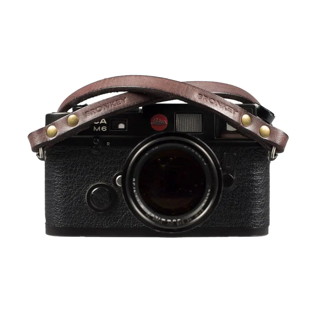 Black camera with a brown leather strap on a white background