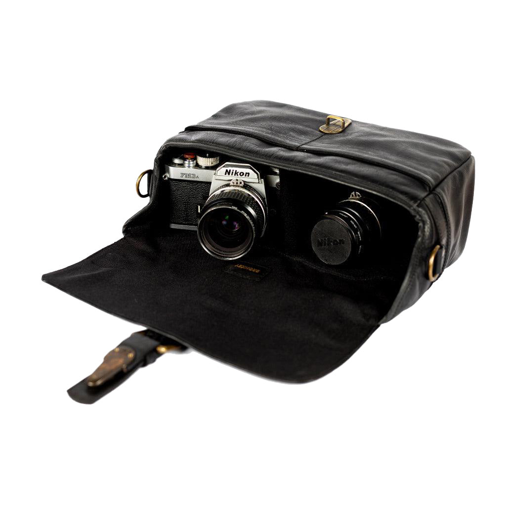Black leather camera bag with a Nikon camera inside on a white background