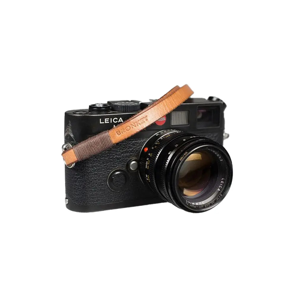 Leica camera with a brown leather strap on a white background