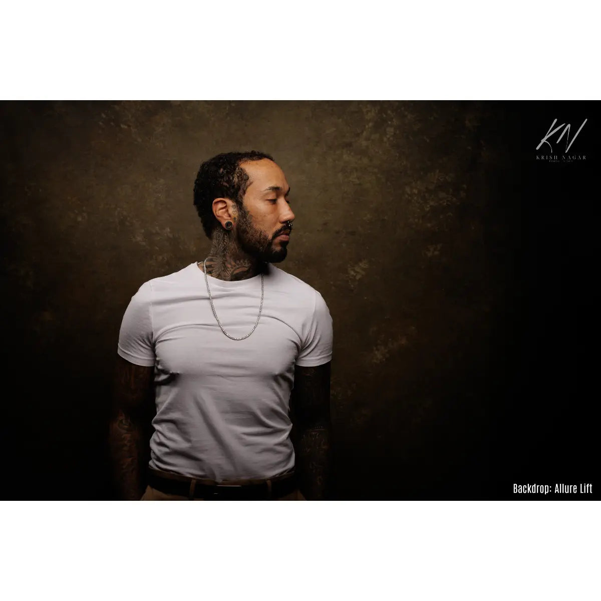 Man wearing a light gray t-shirt against a dark textured backdrop