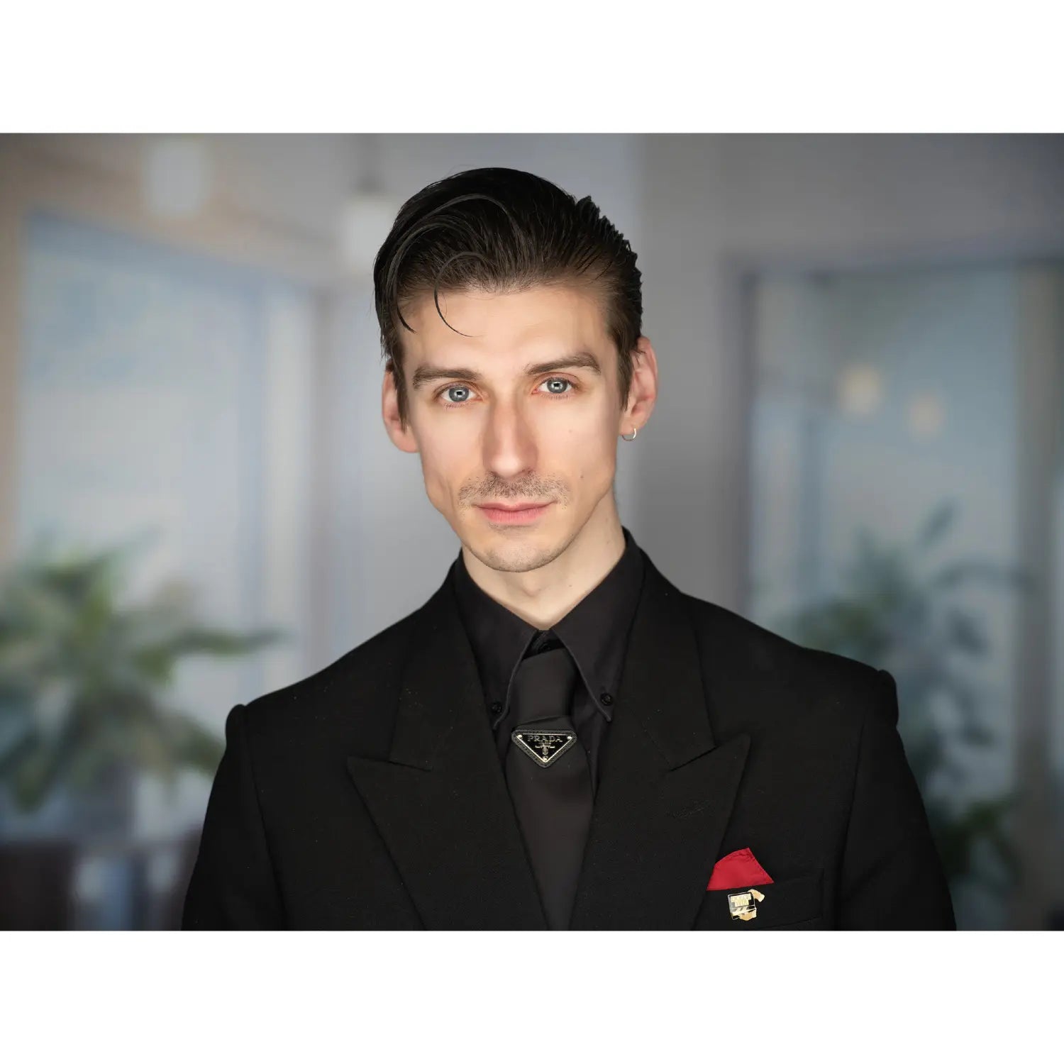 Man in a black suit with a Prada logo in an indoor setting