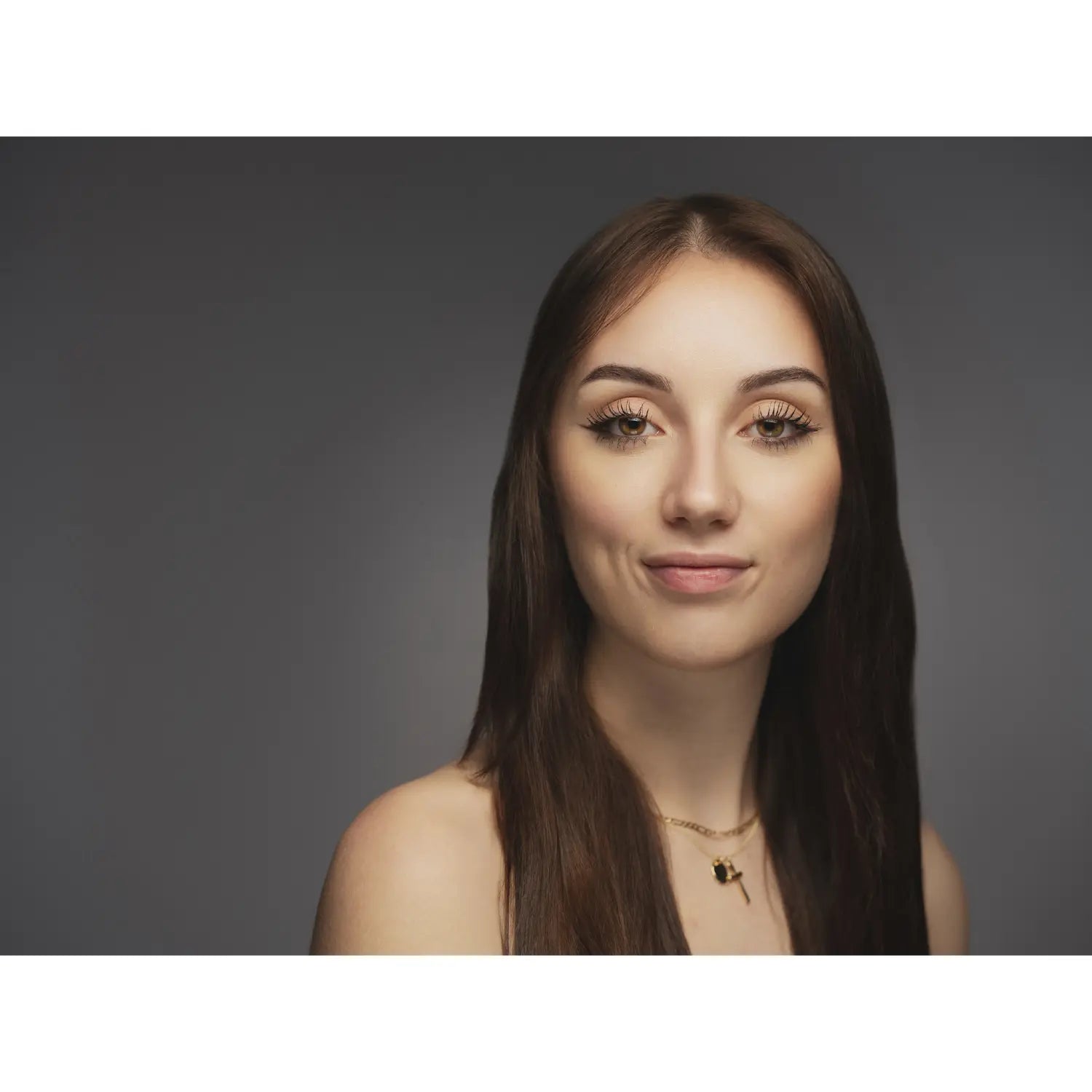 Woman with long brown hair and a neutral expression against a dark background