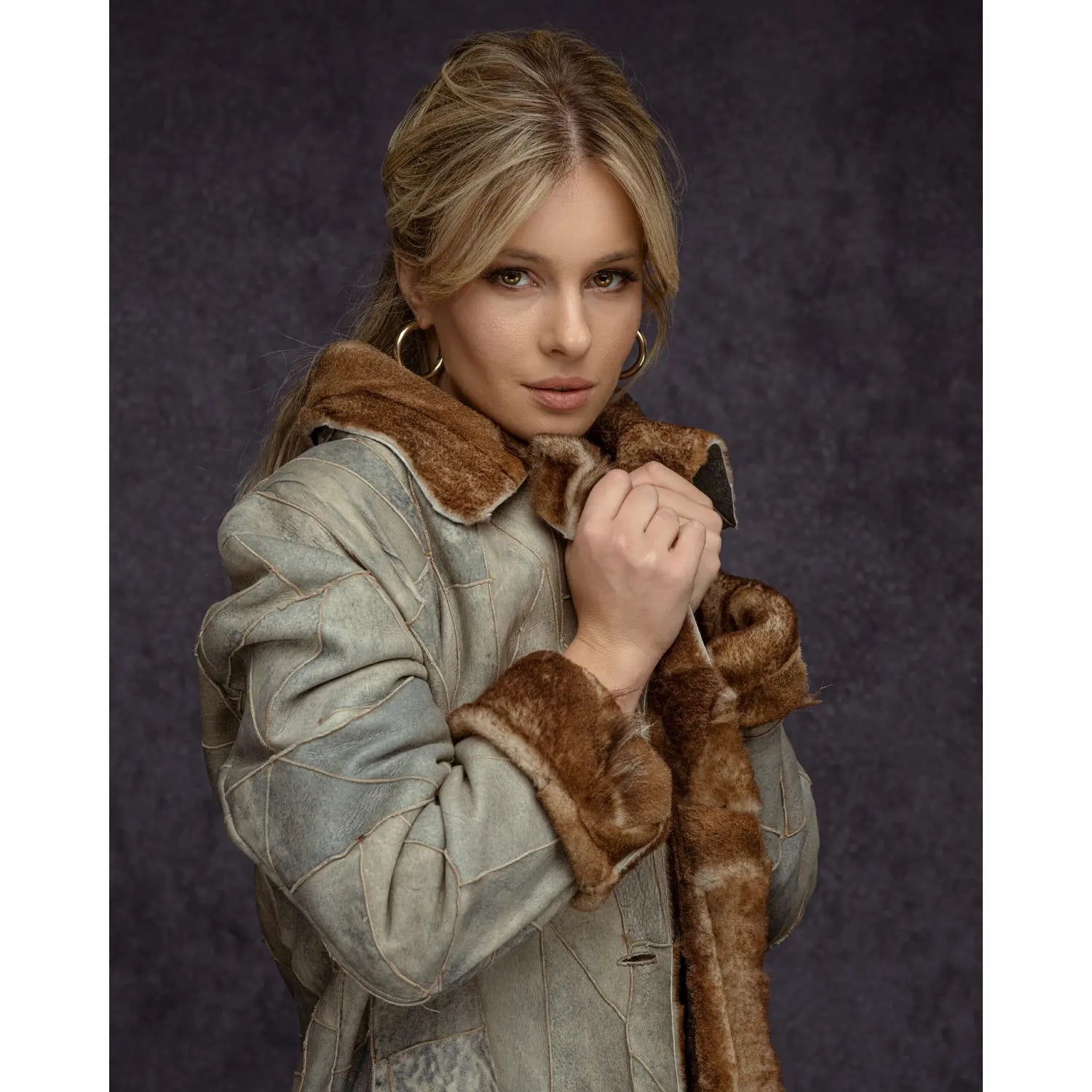 Woman wearing a coat with fur trim against a dark background