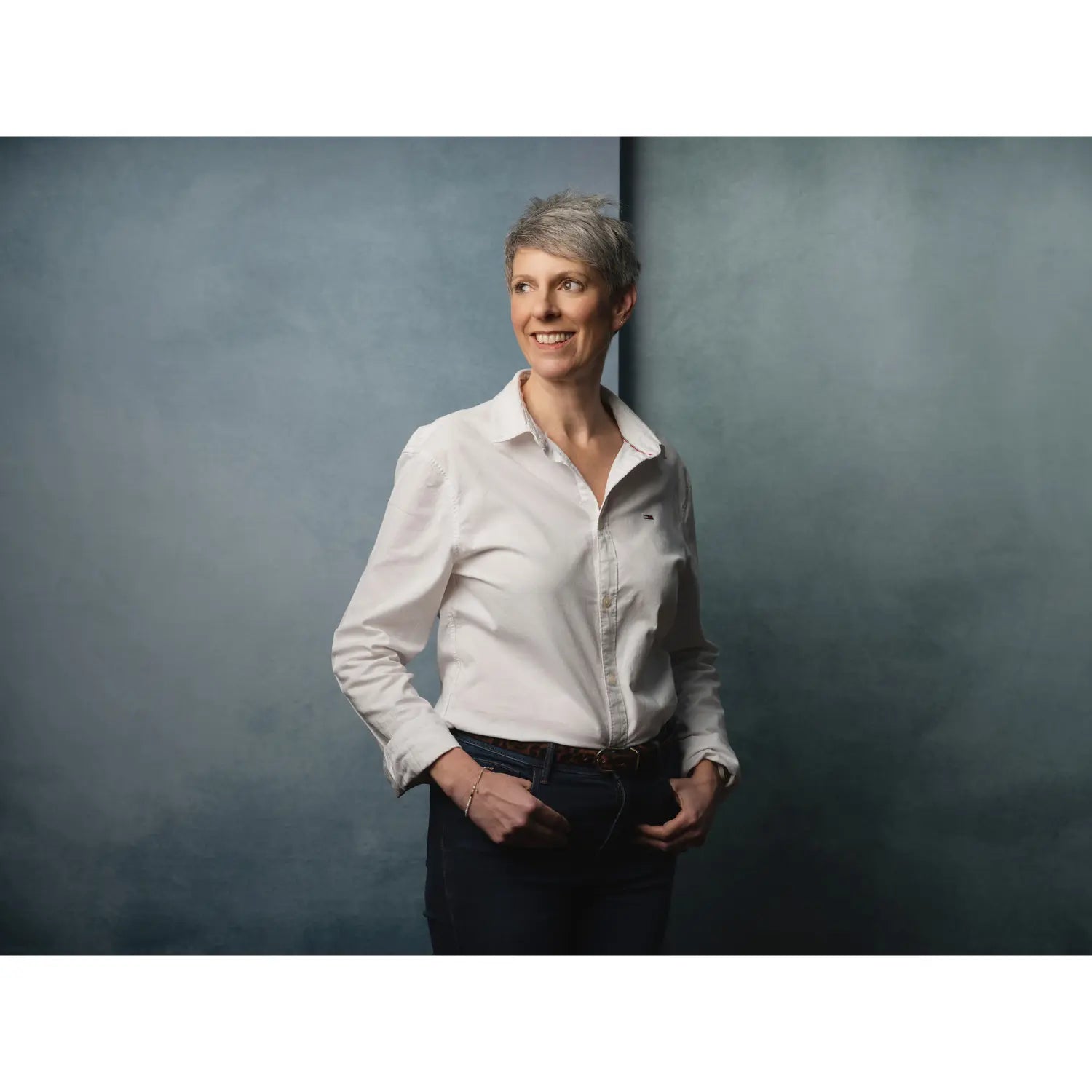 Woman in a white shirt standing against a gray background