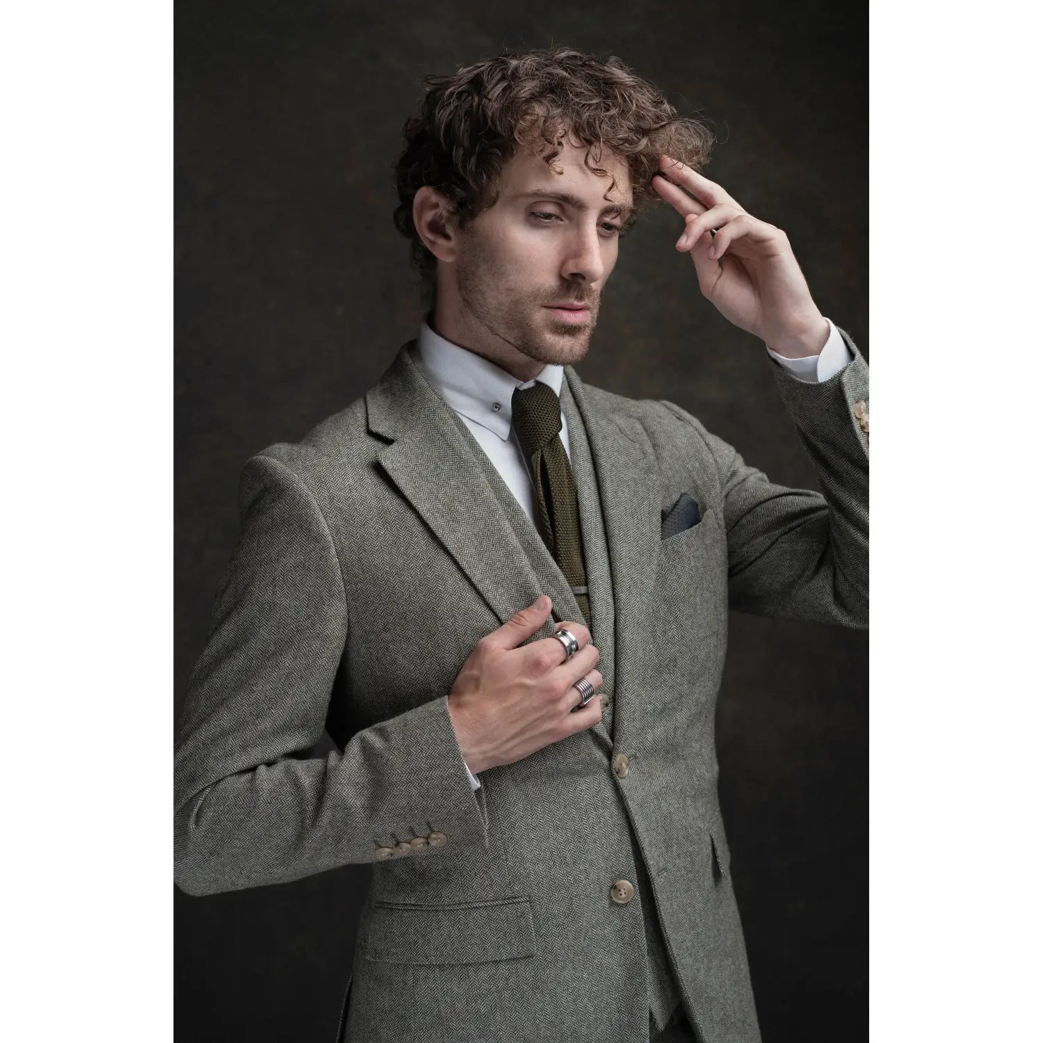 Man wearing a gray suit with a brown tie against a dark background