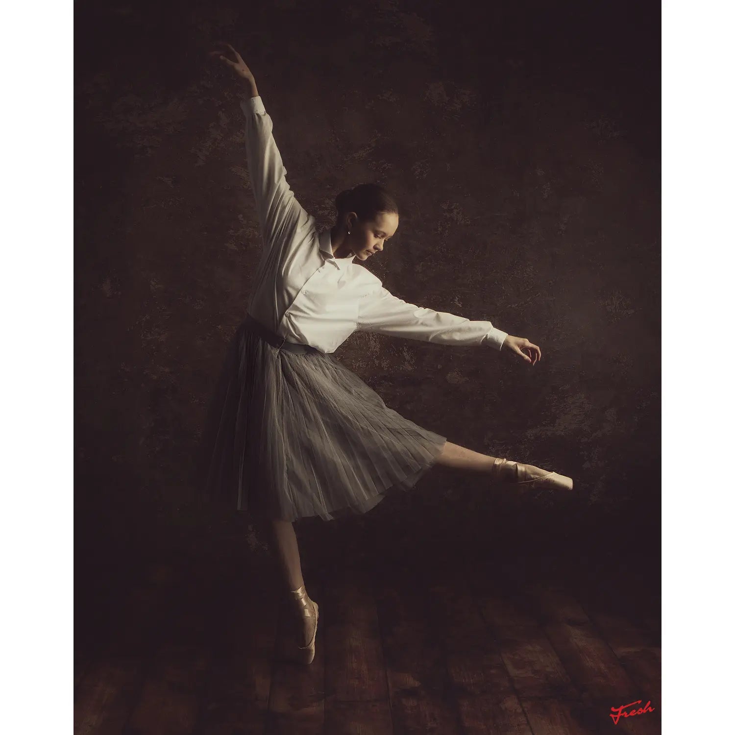 Dancer in a white outfit with one leg extended against a dark background