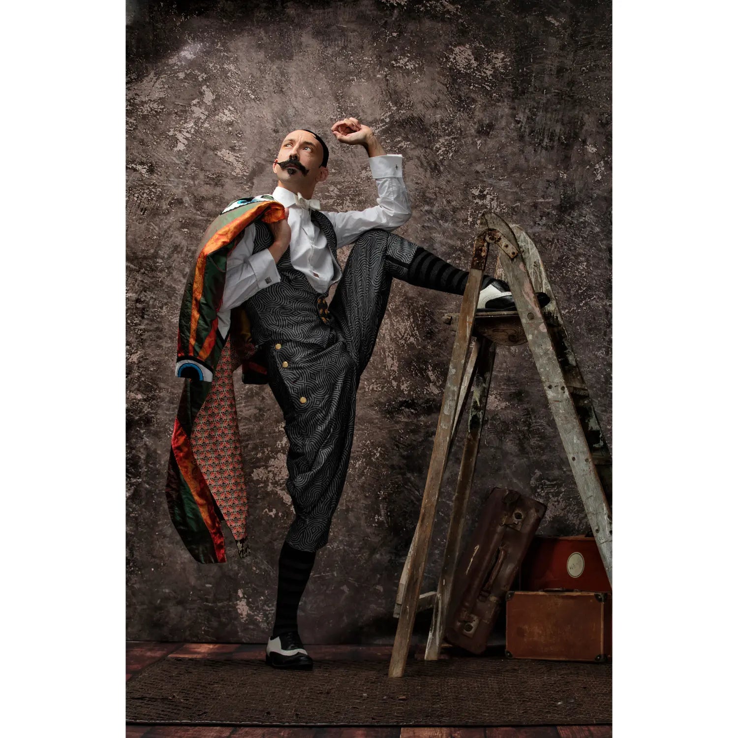 Man in vintage attire posing dramatically against a textured wall.