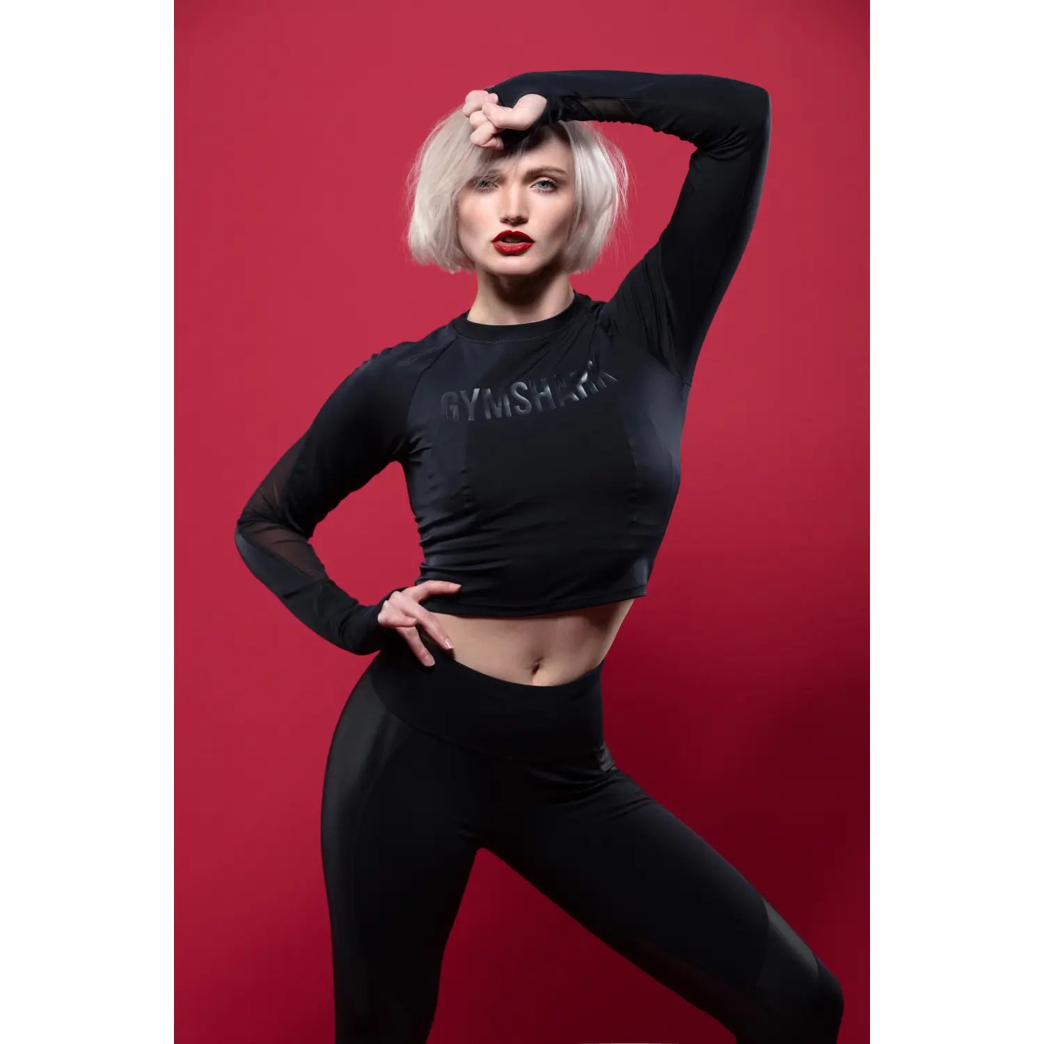 Woman wearing a black 'Gymshark' athletic outfit on a red background
