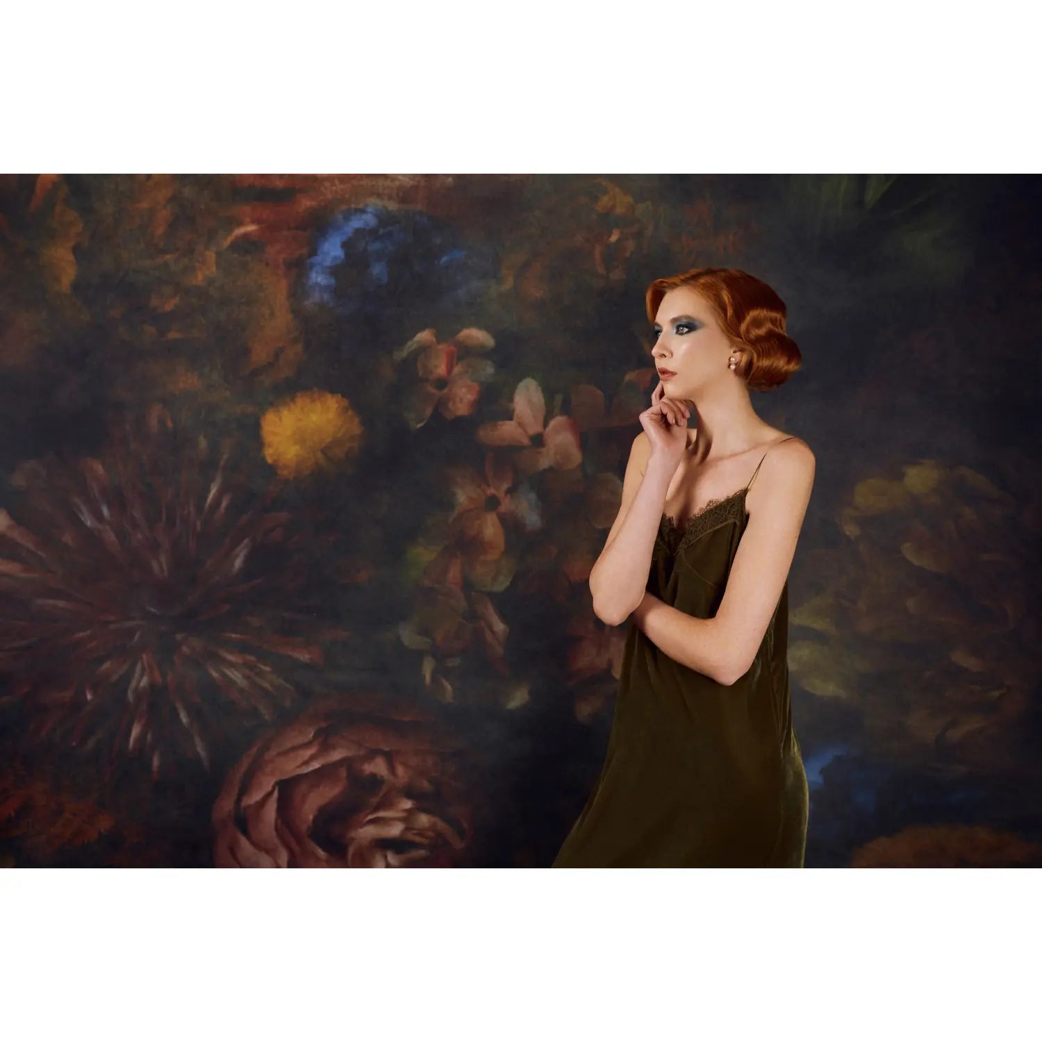 Woman in a green dress standing in front of a floral painting