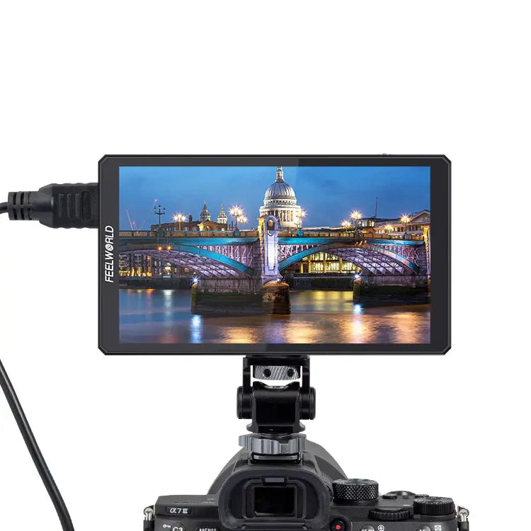 Camera monitor displaying a cityscape with a bridge and buildings at night, connected to a camera.