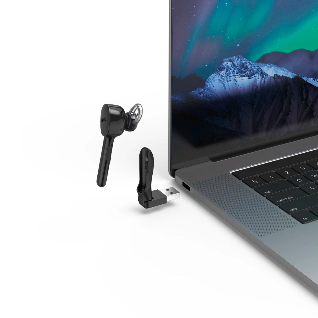Black wireless earbuds and USB receiver next to a laptop displaying a scenic wallpaper.