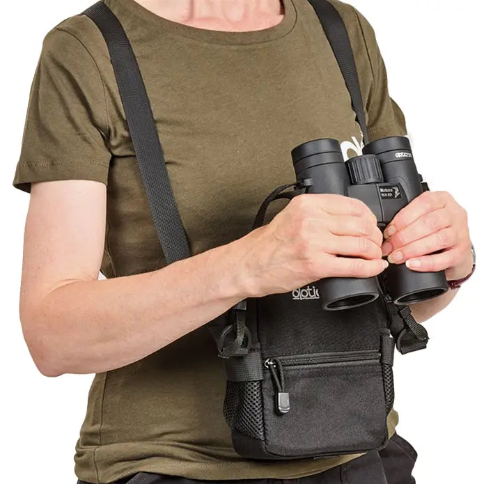 Person holding binoculars with a backpack strap over shoulder on a white background