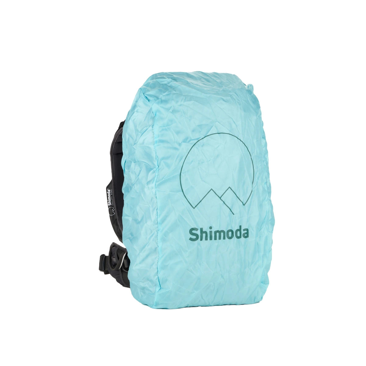 A light blue waterproof backpack cover by Shimoda, featuring a dark green minimalist mountain and sun logo with the brand name printed below, shown on a white background.