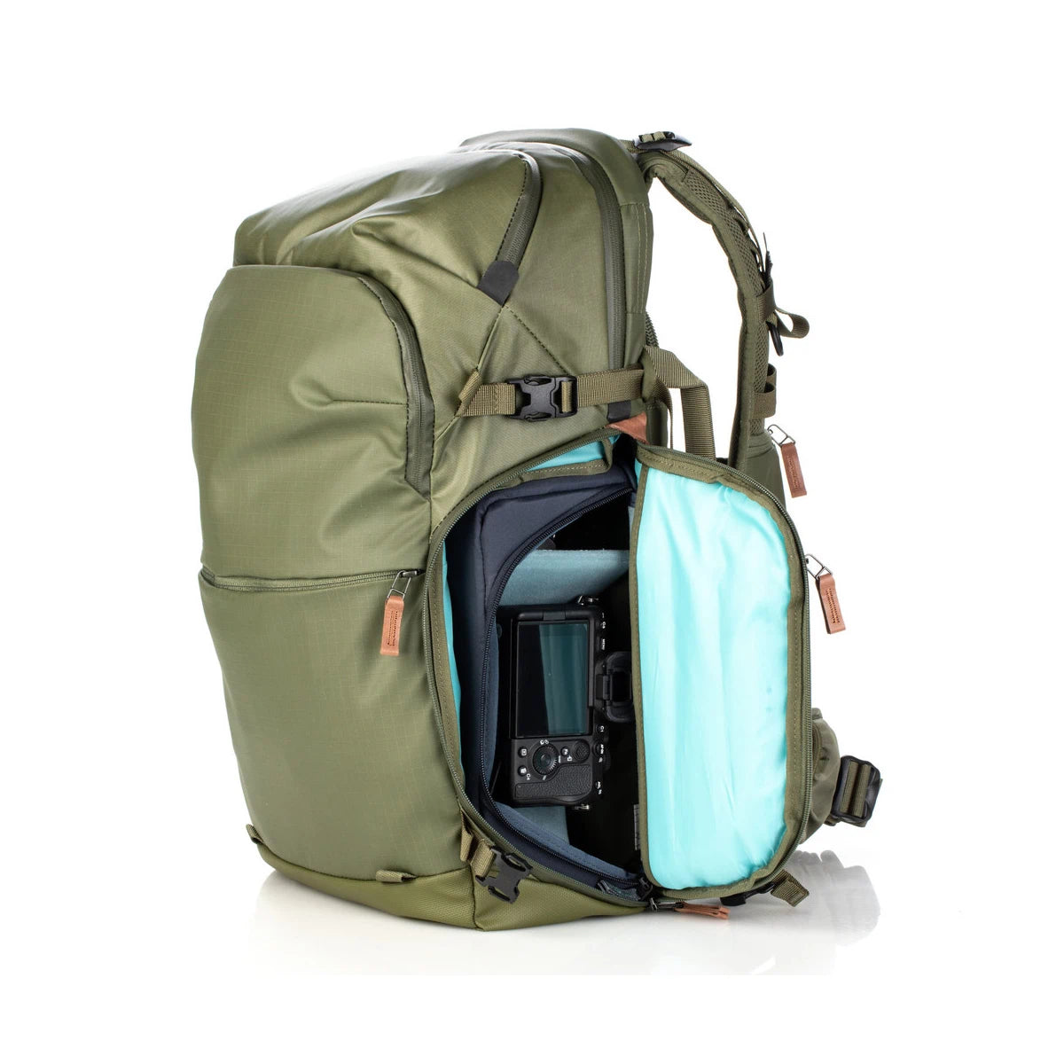 Green backpack with open front compartment showing a camera and blue lining on a white background