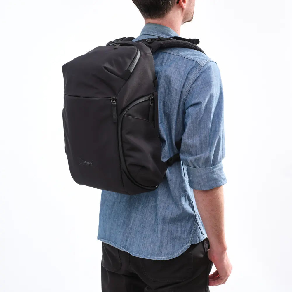 Person wearing a black backpack on a white background
