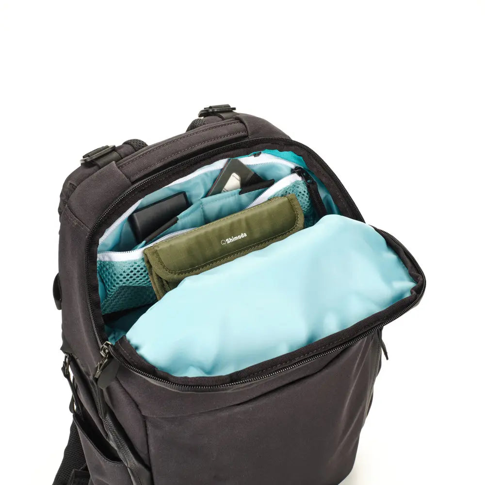Open black backpack with teal interior on a white background