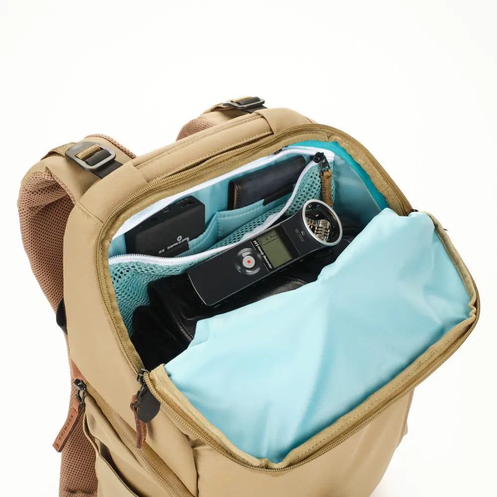 Beige backpack with a blue interior, containing electronic devices.