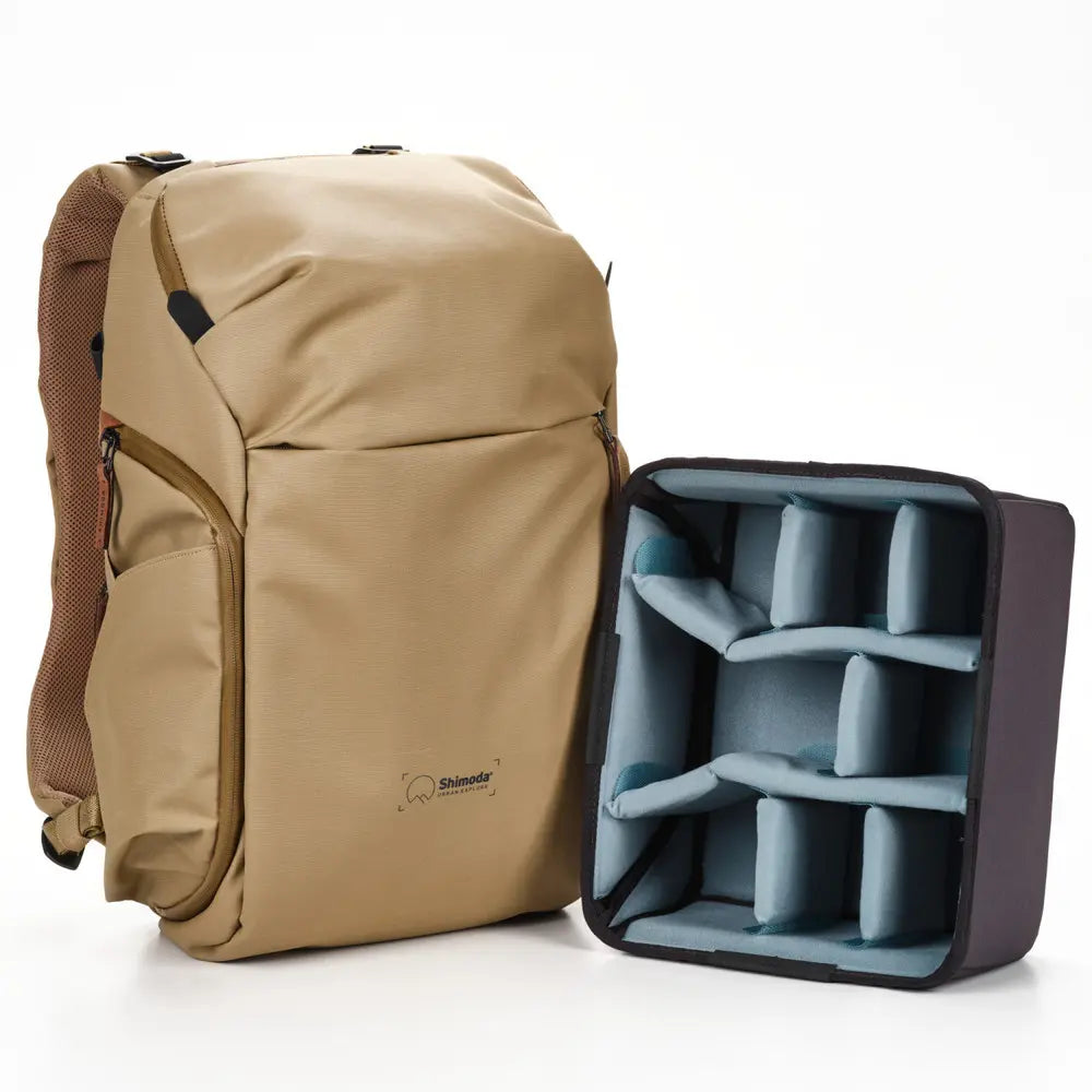 Beige backpack with a compartment showing blue interior padding on a white background