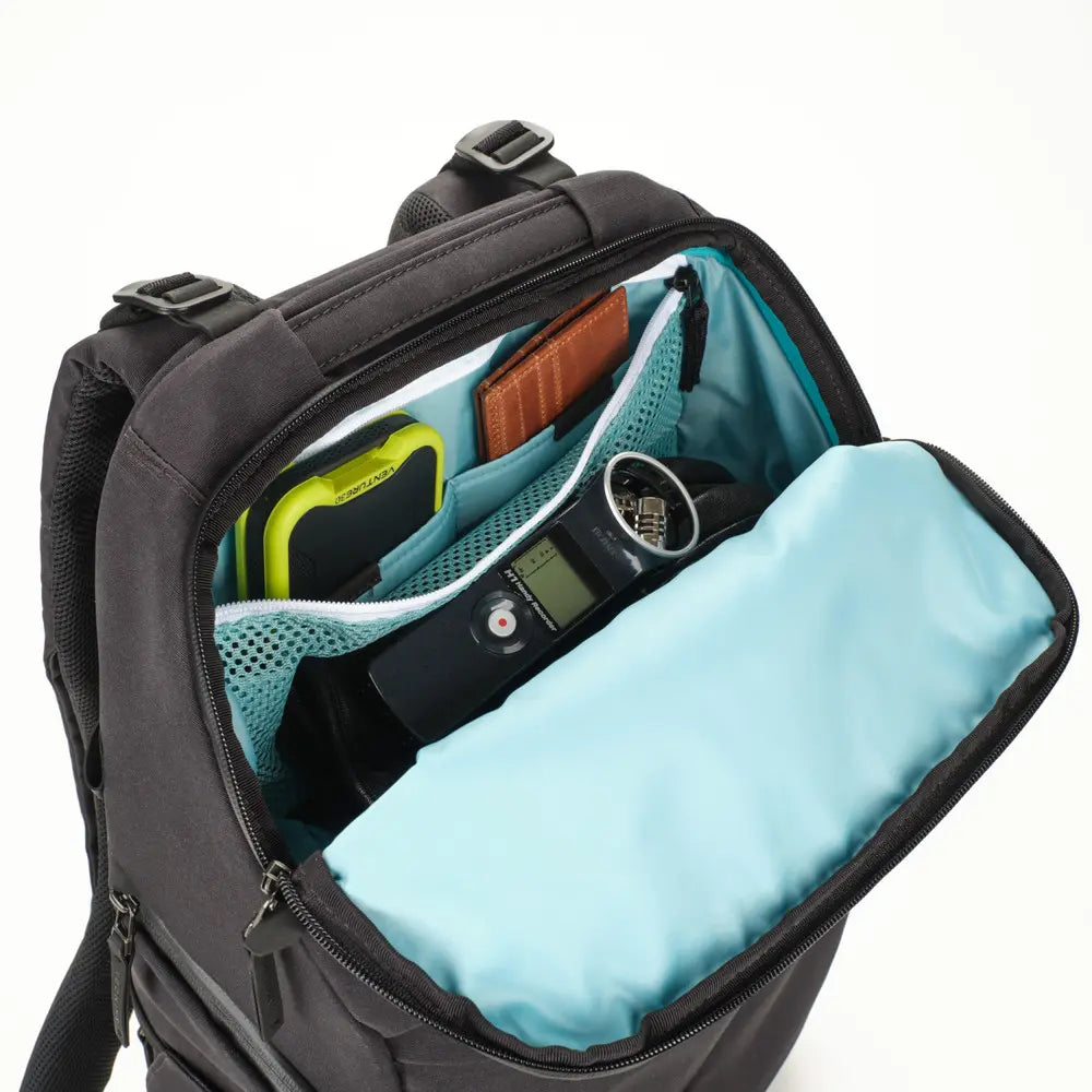 Black backpack with open front compartment showing electronic devices on a white background