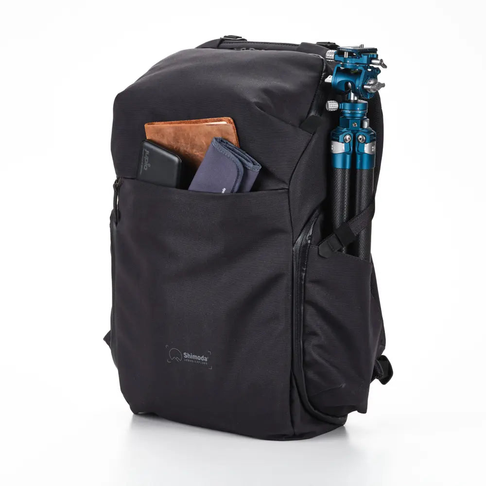 Black backpack with a camera tripod and other items on a white background