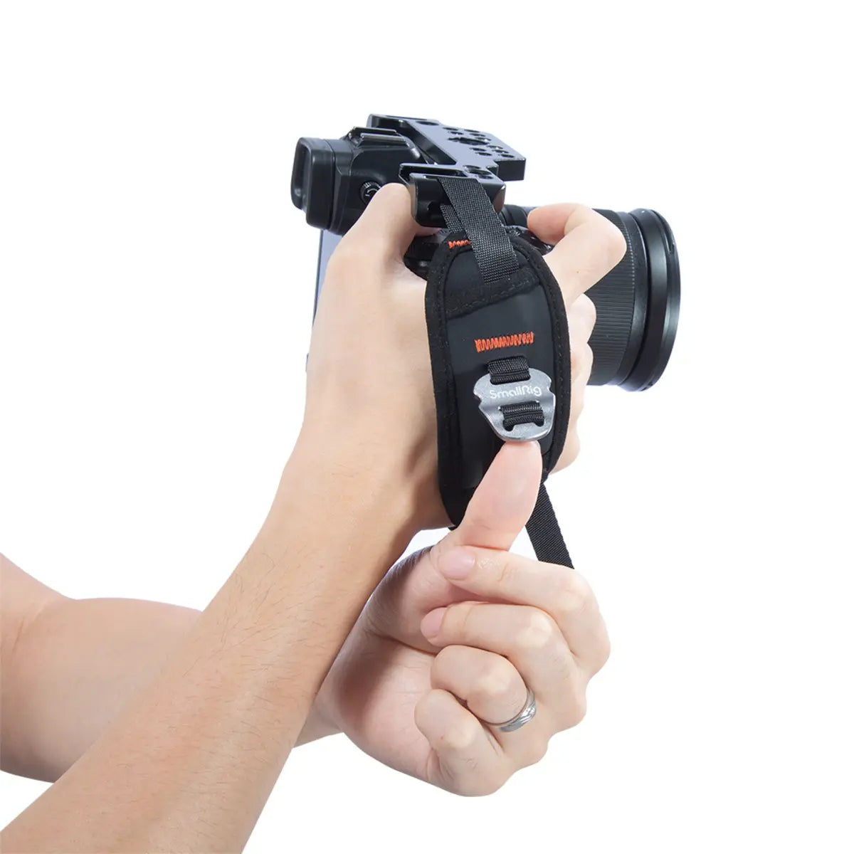 Camera with a strap held by a person's hand on a white background