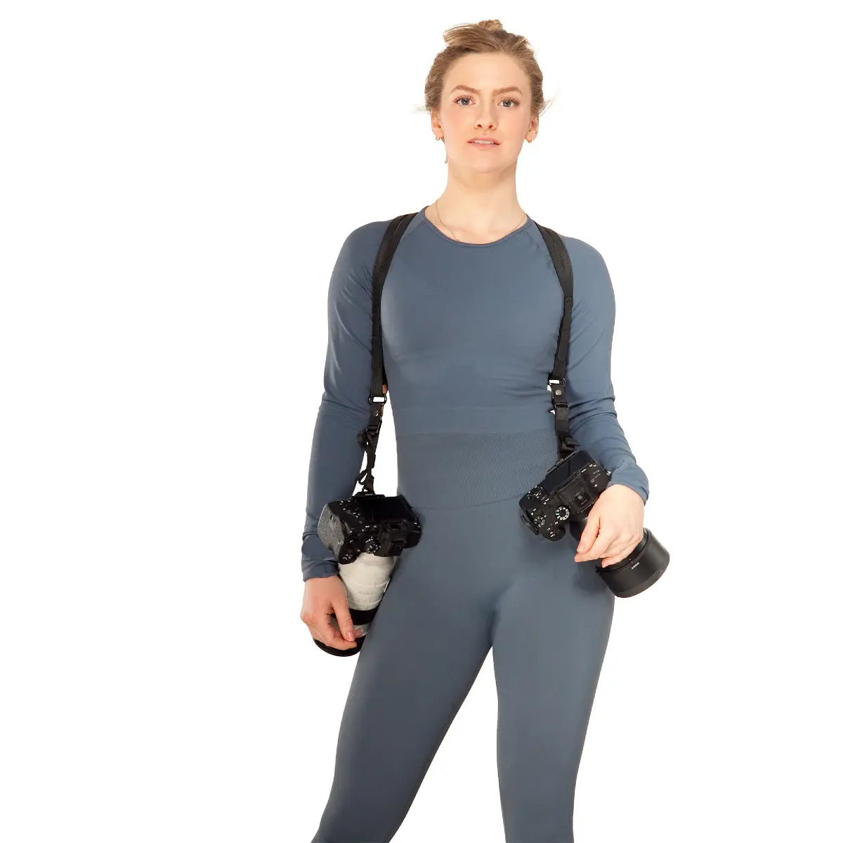 Person wearing a gray outfit with black straps over shoulders on a white background