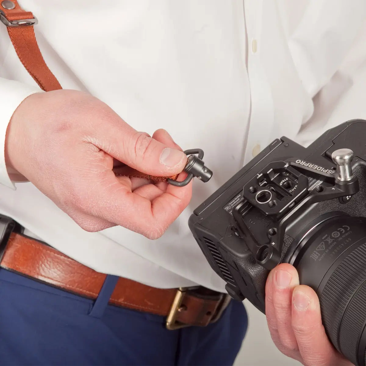 Person attaching a camera strap to a camera