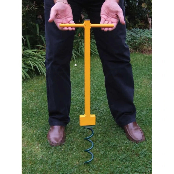 Person holding a yellow garden tool with a spiral handle on grass