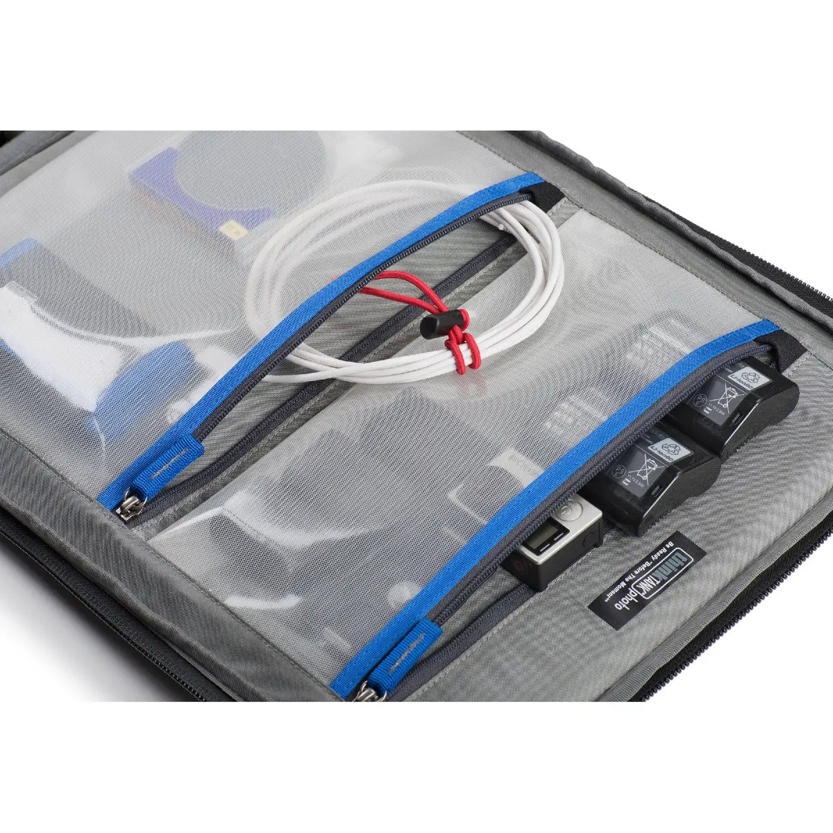 Clear organizer with blue zippers containing electronic components on a white background