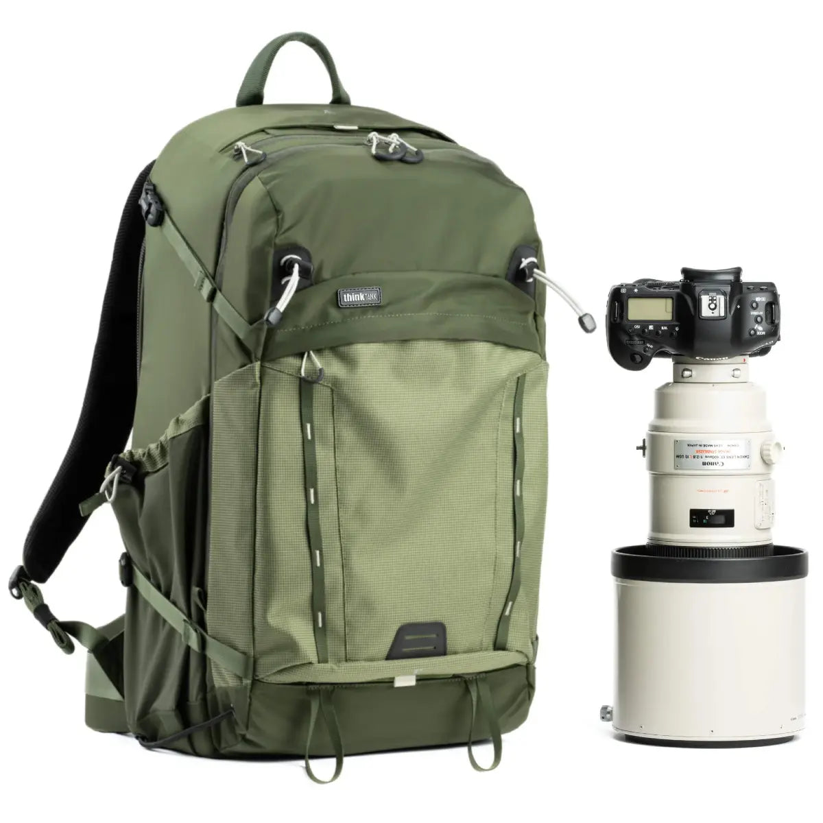 Green backpack next to a camera with lenses on a white background