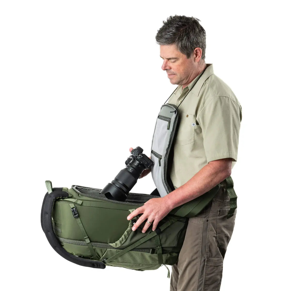 Man holding a large green camera bag with a camera inside on a white background