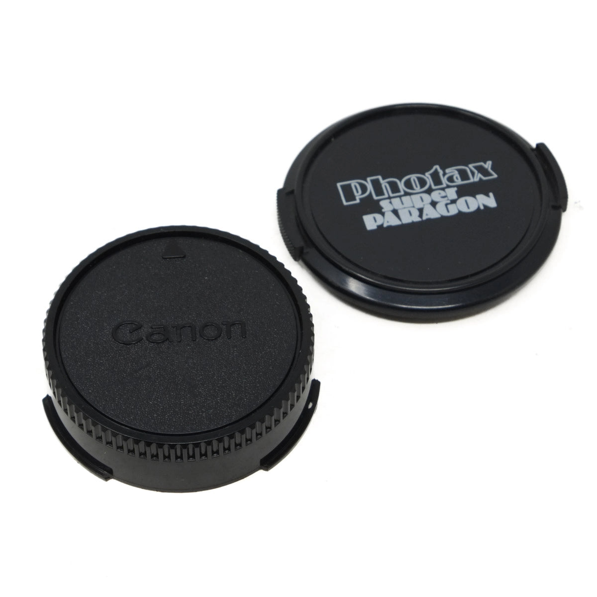 Two camera lens caps, one with Canon logo and the other with Photax Super Paragon logo, on a white background.