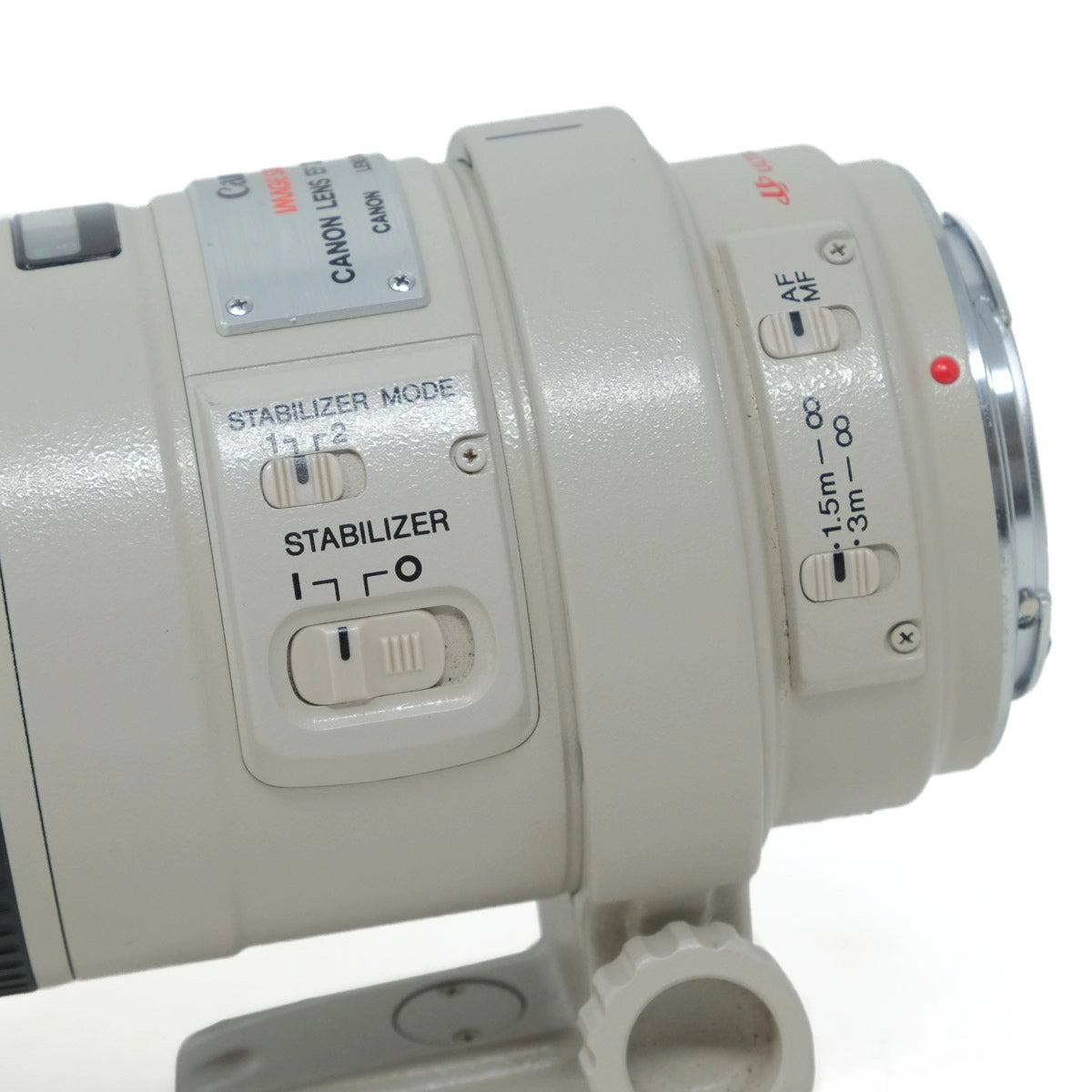 Close-up of a Canon camera lens with control buttons on a white background