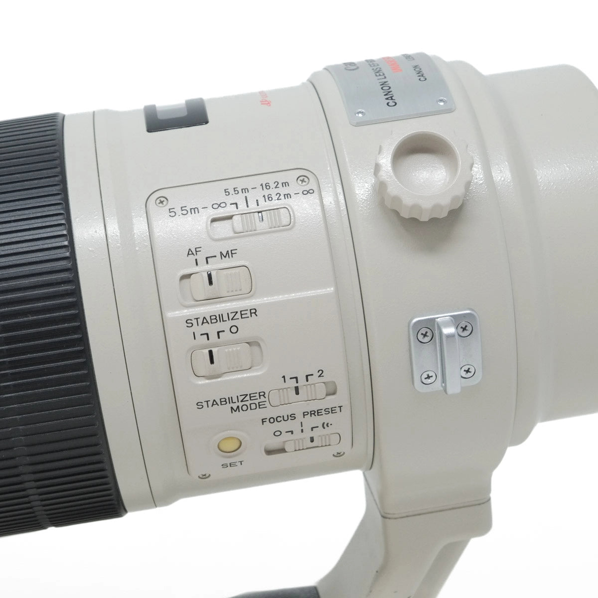 Close-up of a Canon camera lens with control buttons on a white background