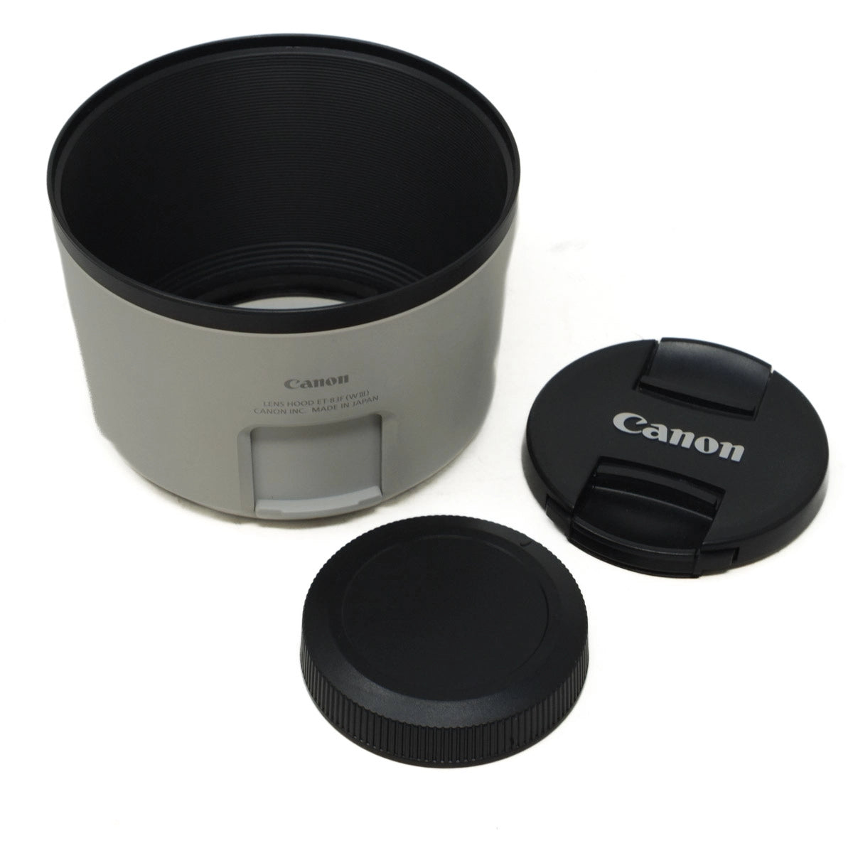 Canon camera lens hood with two lens caps on a white background