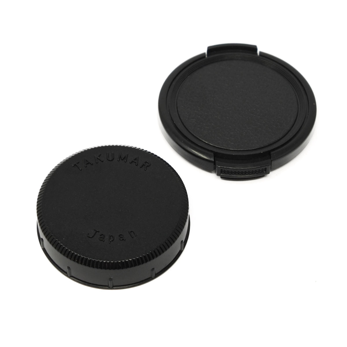 Two black camera lens caps with 'Takumar Japan' branding on a white background