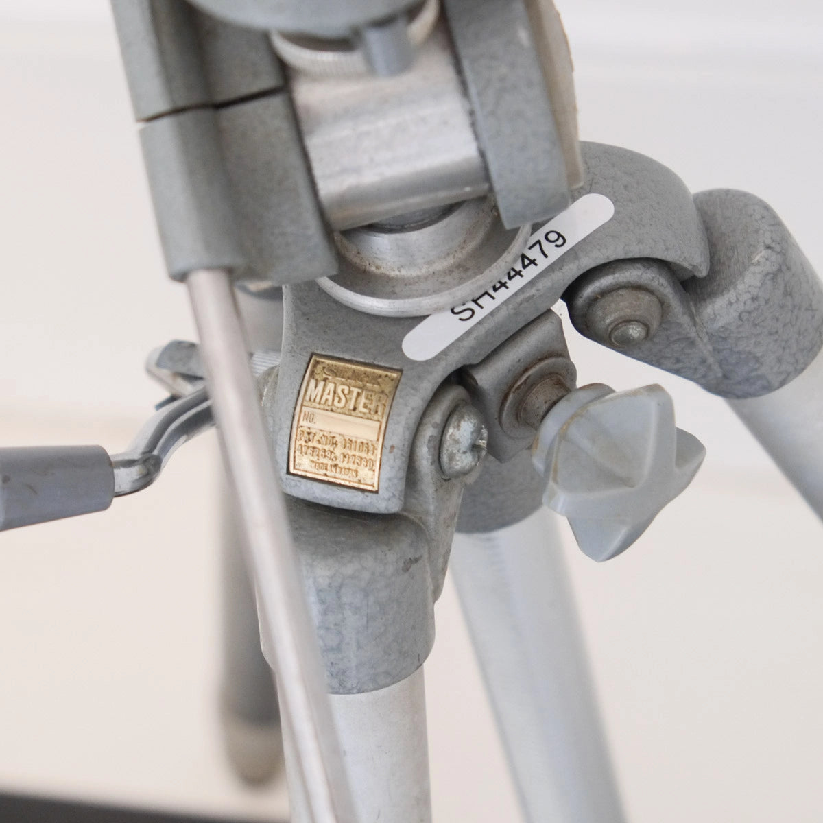 Close-up of a gray tripod with a visible brand label on a light background
