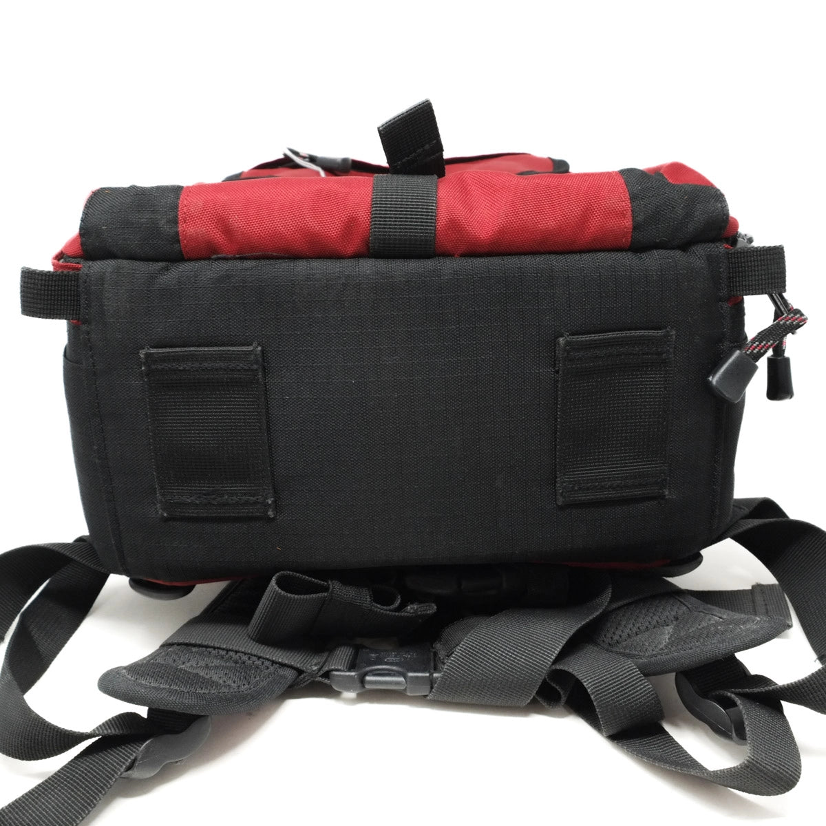 Black and red backpack with multiple straps on a white background