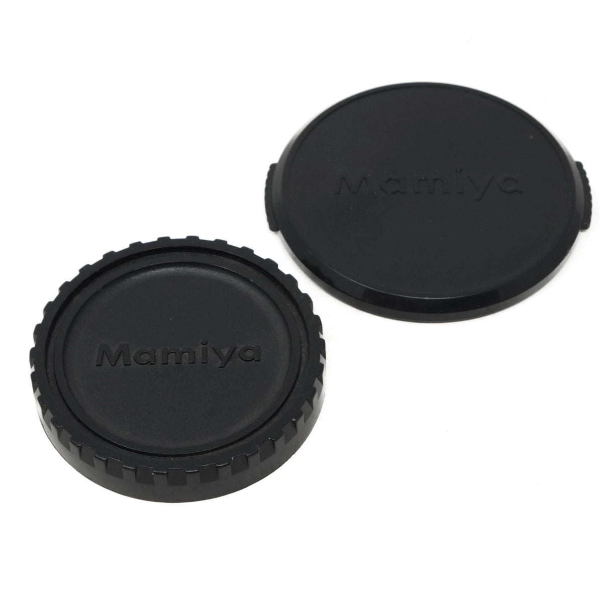 Two black Mamiya camera lens caps on a white background