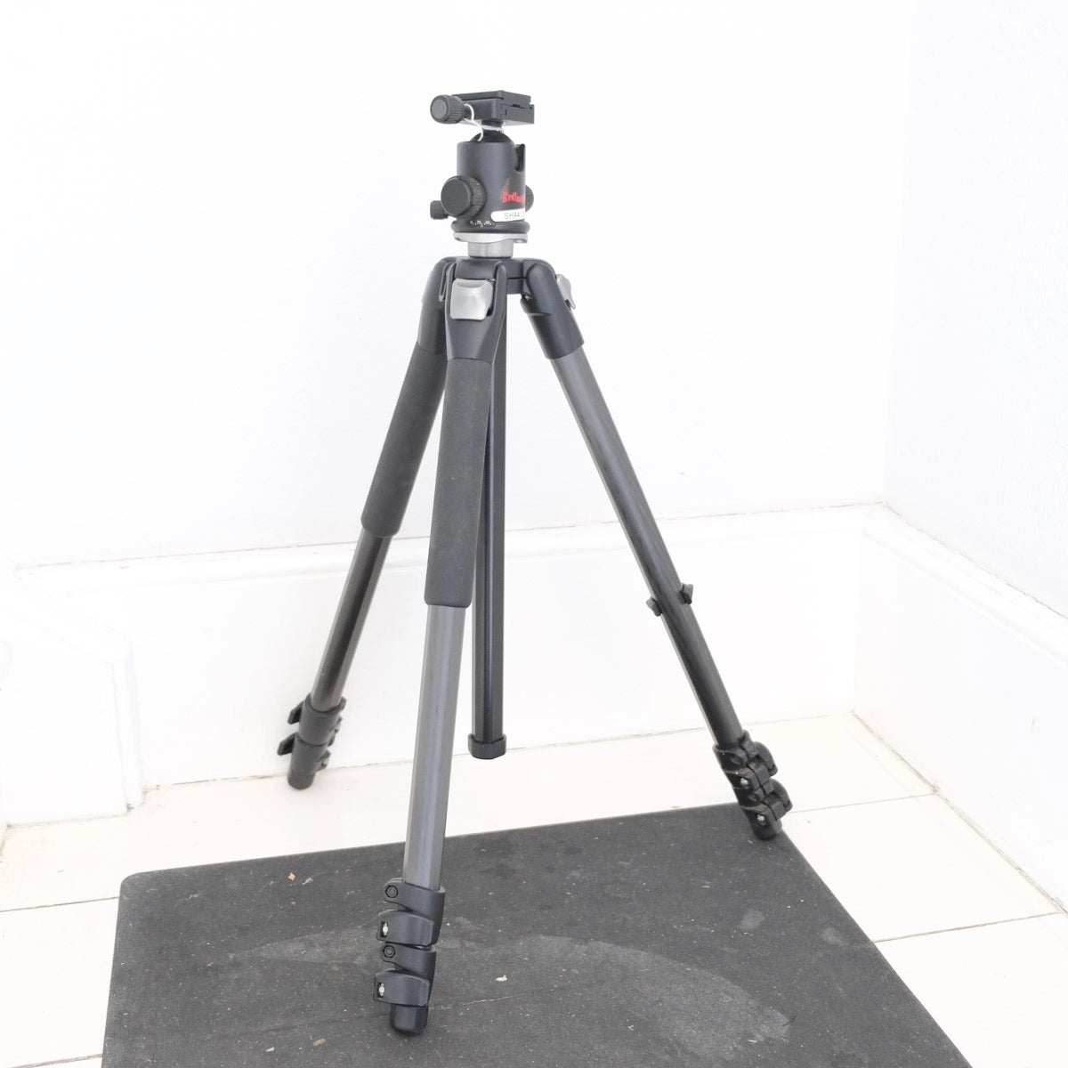 Black camera tripod on a white floor