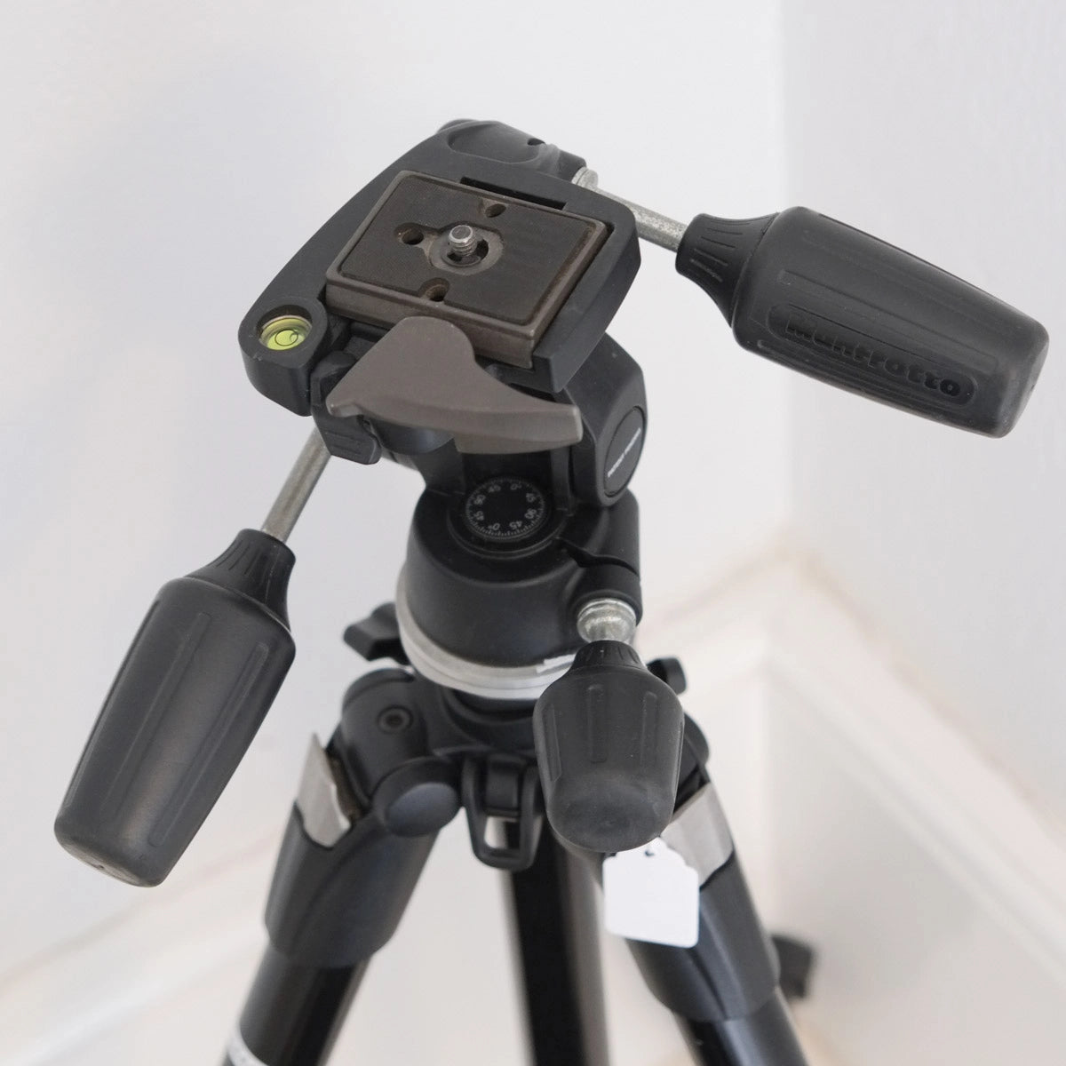 Black tripod with adjustable head on a white background