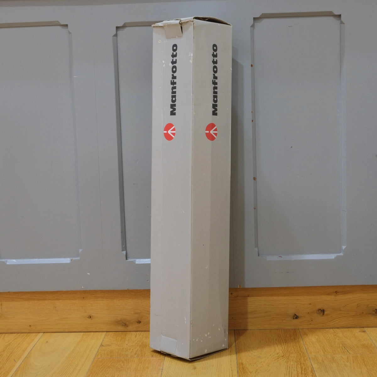 Manfrotto product packaging box standing upright against a plain wall.