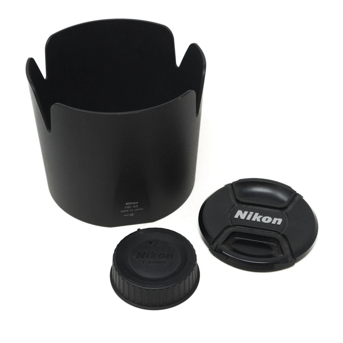 Black camera lens hood and caps with Nikon branding on a white background
