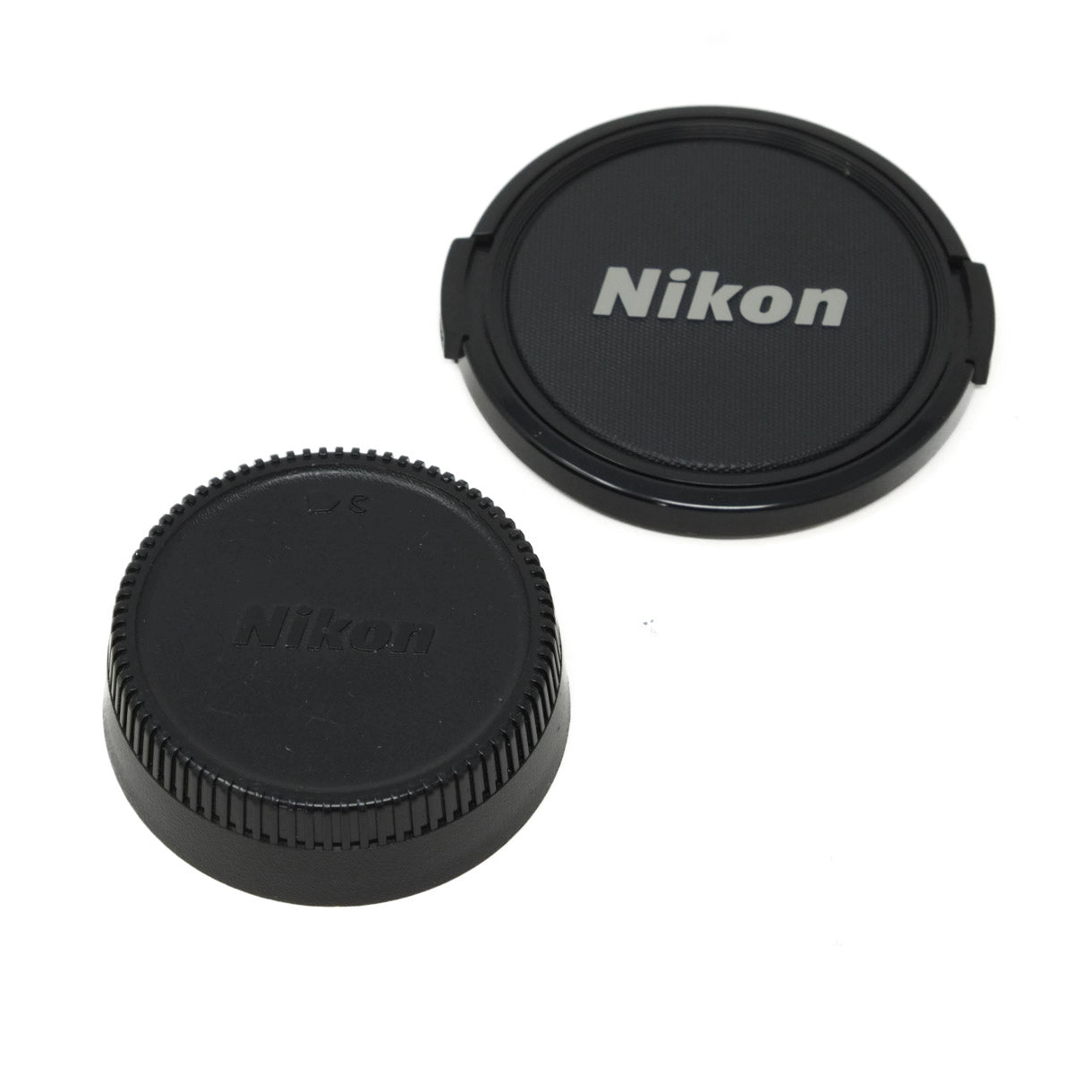 Two Nikon lens caps on a white background