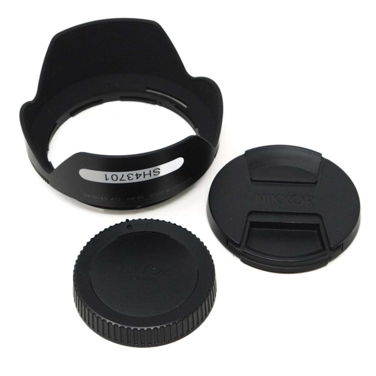 Set of camera lens accessories including a lens hood, front and rear caps on a white background